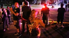 A woman joins others gathered at the scene of a police-involved shooting in Falcon Heights, Minnesota, on July 6. Philando Castile, 32, was fatally shot by police during a traffic stop. His fiancee, Diamond Reynolds, live-streamed the aftermath on Facebook. The shooting is being investigated.