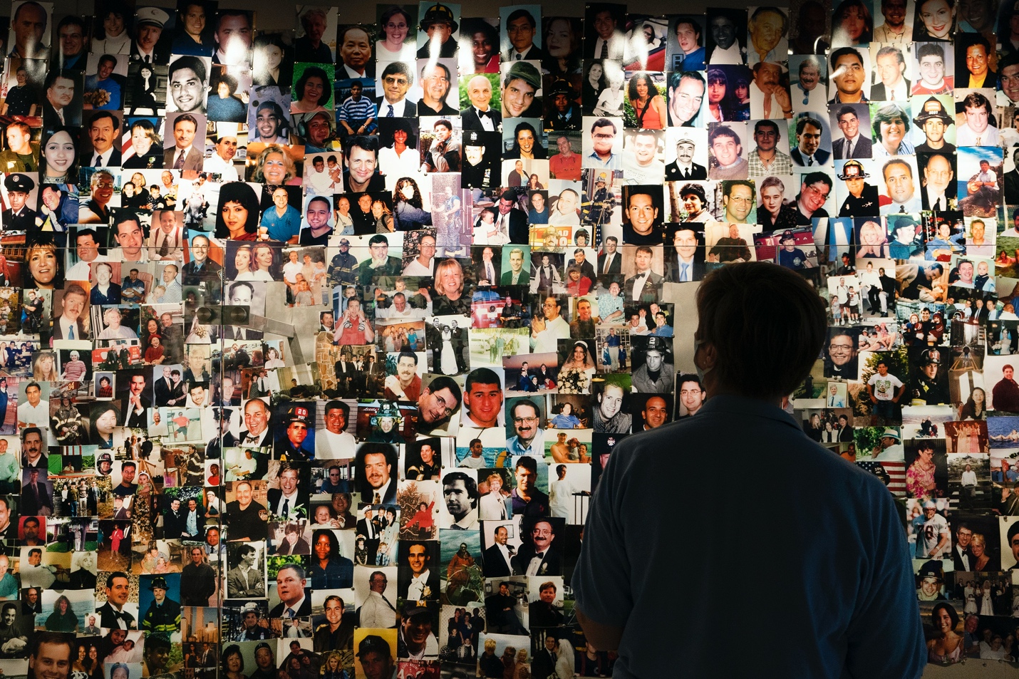 A survivor of the 9/11 attacks on the World Trade Center looks at photos of those who perished, in a display at the 9/11 Tribute Museum, Aug. 6, in New York. — Mark Lennihan, Associated Press